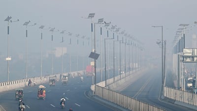 Commuters ride along a street as smog wreathes the Pakistani city of Lahore. AFP