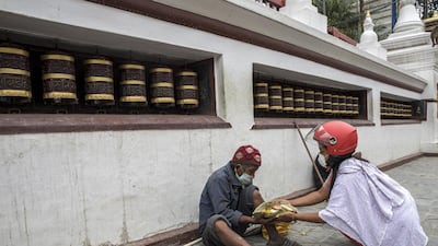 A woman gives food to beggar wearing a masks during the 69th consecutive day of coronavirus lockdown in Kathmandu, Nepal. EPA