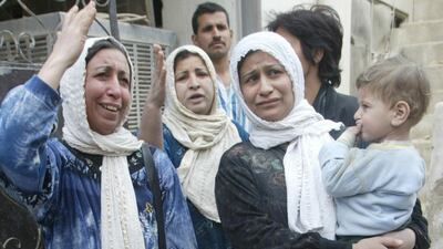 Women grieve outside a house destroyed in US bombing in Baghdad's al-Aazamiya neighborhood on March 24, 2003. Five members of the same family were killed and at least 28 others wounded when a missile fired by allied warplanes hit houses in the densely populated area in the Iraqi capital, according to residents. AFP
