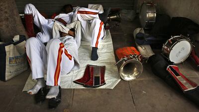 Members of Indian Brass band, specialized playing in weddings, rest on reaching the spot from where the procession is supposed to start, in New Delhi.