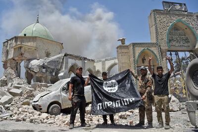 Members of the Iraqi Counter-Terrorism Service hold the ISIS flag upside-down outside the destroyed Al Nuri Mosque in the Old City of Mosul on June 30, 2017. AFP