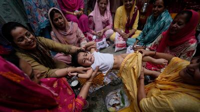 Hindu women from the Dogra community swing a child as part of a ritual as they pray for the long life of their sons, during the Bacch Dua festival in Indian-administered Jammu and Kashmir. AP