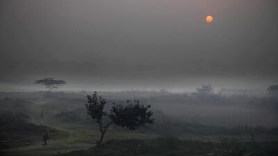 Indians, living in shanties in a farmland, walk as the sun rises in New Delhi, India. Some 800 million people in the country live in poverty, many of them migrating to big cities in search of a livelihood and often ending up on the streets. Altaf Qadri / AP Photo