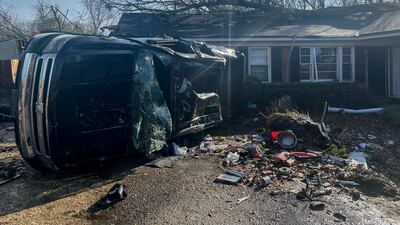 A damaged vehicle rests on its side in front of a home in Selma. AP