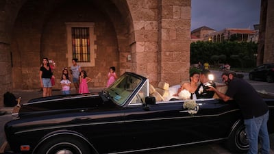 A couple they sit in a classic car after their wedding in Batroun.