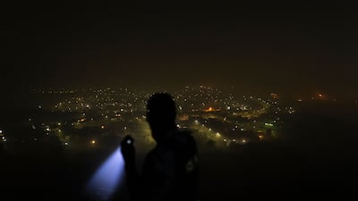 A private security guard scouts the surroundings using his torchlight from a hill facing Mount Moriah suburb in North of Durban. Countrywide blackouts of up to 12 hours a day are rolling across South Africa. AFP