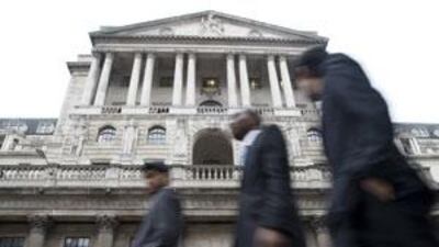 Workers pass the Bank of England in the City of London, which is now the focus of public anger over employee bonuses.