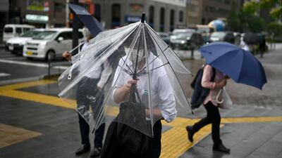 A man tries to shelter under an umbrella as rain and wind from the country's rainy season affects Tokyo. AFP