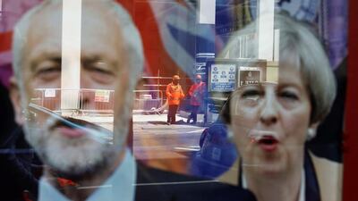 Workers in protective equipment are reflected in the window of a betting shop displaying images of Britain's prime minister Theresa May and opposition Labour Party leader Jeremy Corbyn in London on June 7, 2017. Marko Djurica / Reuters