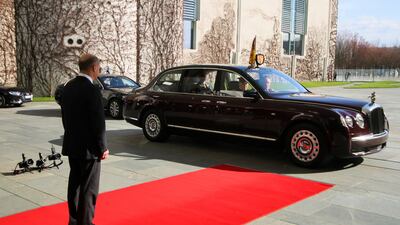 Mr Scholz waits as the car carrying King Charles arrives. Reuters