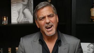 George Clooney poses for photographs on arrival at the book launch of Cindy Crawford at the Beaumont Hotel in central London. Joel Ryan / Invision / AP