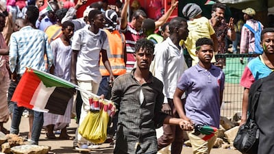 A Sudanese peddlar walks with national flags to be sold during a rally demanding a civilian body to lead the transition to democracy. AFP