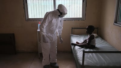 A Liberian Ministry of Health worker, dressed in an anti-contamination suit, speaks to Banu, 4, in a holding centre for suspected Ebola patients at Redemption Hospital in Monrovia, Liberia. John Moore/Getty Images