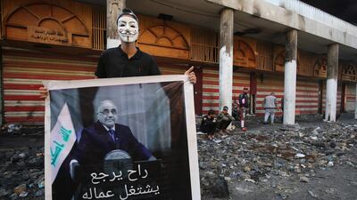 An Iraqi protester holds a picture of the newly resigned prime minister Adel Abdel Mahdi. AFP