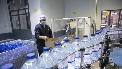 A machine operator, works away inside the packaging room for the 5-gallon water at the Al Ain water bottling facility. Silvia Razgova / The National