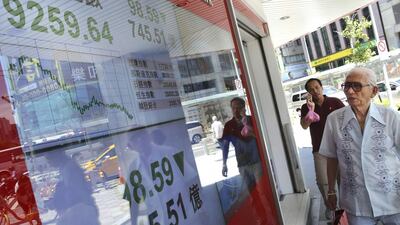 TAIWAN - Pedestrians pass by a Taiwan Stock Exchange monitor showing a drop in the market at close. Wally Santana / AP Photo