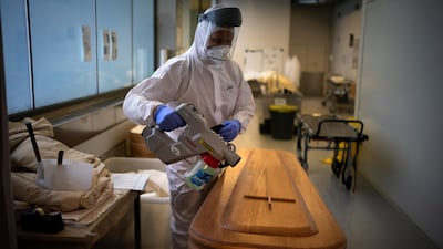 A mortuary worker disinfests a coffin carrying the body of a person who died of Covid-19 in Girona, Spain. Spain's health ministry said Wednesday that the nation has surpassed 60,000 fatalities. AP Photo
