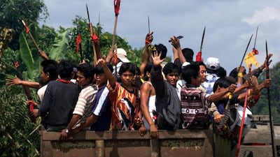 Dayaks brandishing spears and machetes roam the streets looking for Madurese migrants on the outskirts of Sampit in Central Kalimantan province, Borneo Island, on February 23, 2001. Charles Dharapak / AP Photo