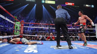 Referee Kenny Bayless, cetner, looks towards Manny Pacquiao, left, as he lies face down on the mat after being knocked out by Juan Manuel Marquez. John Gurzinski / AFP