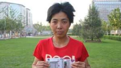 Jin Hanyan, pictured before her detention in a Beijing black house, holds photographs of a black house in her home province of Hubei.