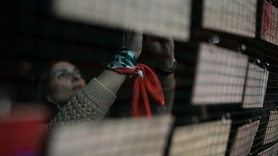 An anti-government protester wears a scarf with the national flag on her wrist as she places a personal message on the base of the protesters' Christmas tree, which incorporates protest iconography and slogans and personal messages at a celebration in downtown Beirut. AP Photo