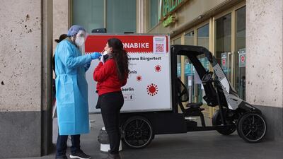 A medical assistant takes a swab sample for a Covid-19 test from a woman at a "Coronabike" mobile testing station in Berlin, Germany. Getty Images