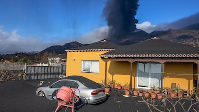 Ash covers a house, car and garden as in the background a volcano erupts on the Canary island of La Palma, Spain. AP Photo