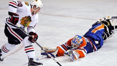 Chicago Blackhawks' Brandon Saad is checked by Edmonton Oilers goalie Devan Dubnyk.