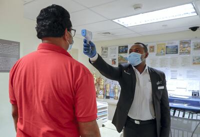 A hotel employee is checked by a security officer before entering the workplace. Victor Besa/The National
