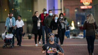 People wearing protective masks pass through Inner Harbor in Baltimore, Maryland, US. Coronavirus infections continue to rise in the greater Washington region, with more than 5,000 new cases reported on Thursday, a daily record. Bloomberg