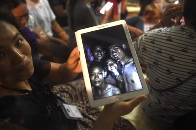 A tearful family member shows the latest pictures of the missing boys taken by divers inside Tham Luang cave in a miracle rescue after days of painstaking searching. LIllian Suwanrumpha / AFP