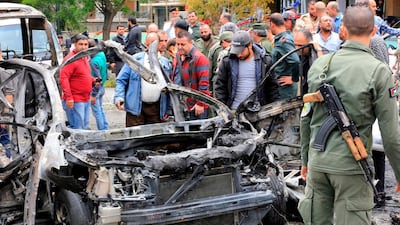 Syrians surround a charred car following an explosion in Damascus on May 9, 2018. Louai Beshara / AFP