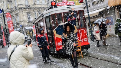 A woman poses for a photograph on a snowy Istiklal Avenue. AFP