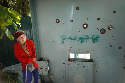 Tetiana Kozhevnikova, 80, looks out of the front gate of her home after it was riddled with holes from a cluster bomb attack in Sloviansk, Ukraine. Getty