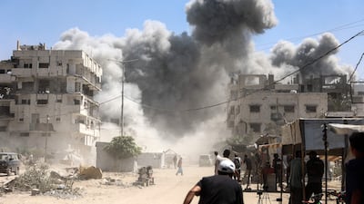 Palestinians watch as the Mhanna tower collapses amid heavy smoke, during an Israeli air strike in the Tal El Hawa neighbourhood of Gaza city. AFP