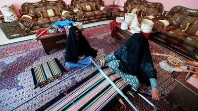 MaShamsa Almazrouei, 80, watches as her daughter Hamda Almazrouei, 46, uses a floor loom to weave a table runner at their home in Madinat Zayed. Sarah Dea / The National