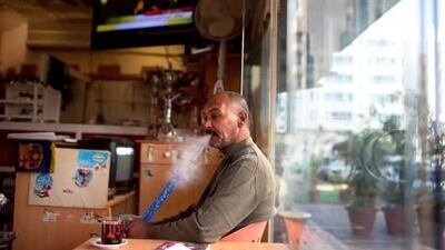Al Hajar Coffee Shop manager Abdul Azim Al Saeed enjoys his afternoon shisha as he works in the cafe in Abu Dhabi.