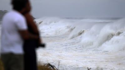 People watch waves as they crash along the shore as Cyclone Freddy nears the island of La Reunion. AFP