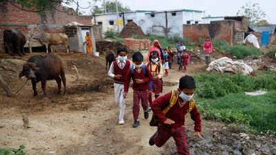Children wearing face masks amid concerns over the spread of coronavirus, return home after knowing that public gatherings and schools are shut following late-night state government order, at a village in Kannauj, in India's most populous state of Uttar Pradesh. AP Photo