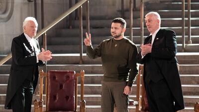 Ukrainian President Volodymyr Zelenskyy, centre, makes a peace sign to MPs in the UK parliament. PA
