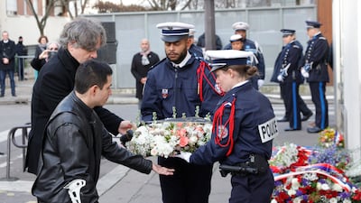 Charlie Hebdo webmaster Simon Fieschi and cartoonist Laurent Sourisseau, also known as Riss, hand over a wreath to police officers during a ceremony marking the eighth anniversary of the extremist attack on the satirical magazine's office. EPA