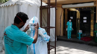 A health worker adjusts the face shield of another as she prepares to go inside a quarantine centre for Covid-19 patients in New Delhi. India now has reported more than 15 million coronavirus infections, a total second only to the US. AP