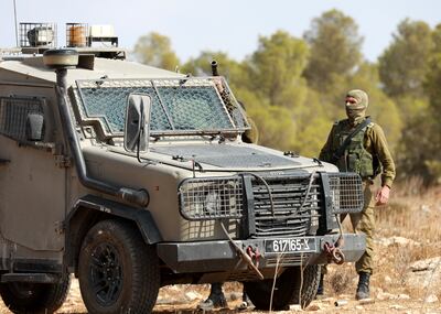 An Israeli solider stands guard as Palestinian farmers harvest olives near the Jewish settlement of Ma'on in the occupied West Bank. EPA