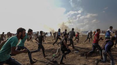 Palestinian protesters run for cover from Israeli tear-gas during clashes after near the border with Israel in the east of Gaza Strip, 15 May 2018
