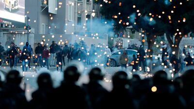 Supporters of Lebanon's Shiite Hezbollah and Amal groups (background) throw fireworks towards Lebanese riot police during clashes on December 14, 2019, in central Beirut. AFP