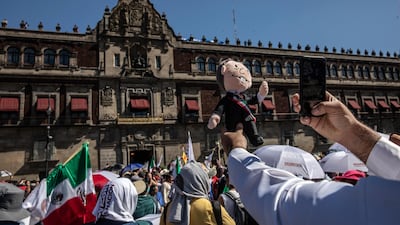 A supporter takes a photograph of a stuffed doll in the likeness of Andres Manuel Lopez Obrador at the central plaza, known as the Zocalo, in Mexico City. Bloomberg