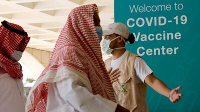 Saudis are greeted by a health worker as they enter a new coronavirus vaccination centre at the Jeddah old airport, Saudi Arabia. AP Photo