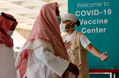 Saudis are greeted by a health worker as they enter the coronavirus vaccination centre at the Jeddah old airport in Saudi Arabia. AP Photo