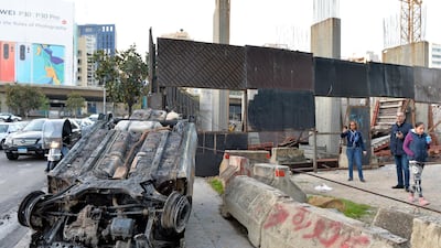 People inspect a burnt-out car. EPA