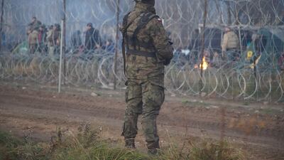 A soldier on guard as migrants gather at the Belarus-Poland border. EPA